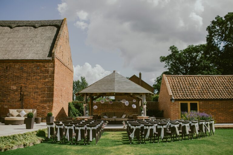 Outdoor wedding ceremony with brown chairs in front of a gazebo and house